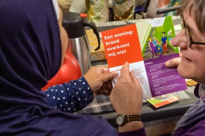 Twee vrouwen bekijken samen een brochure, met kleurrijke achtergronden en gezellige sfeer.